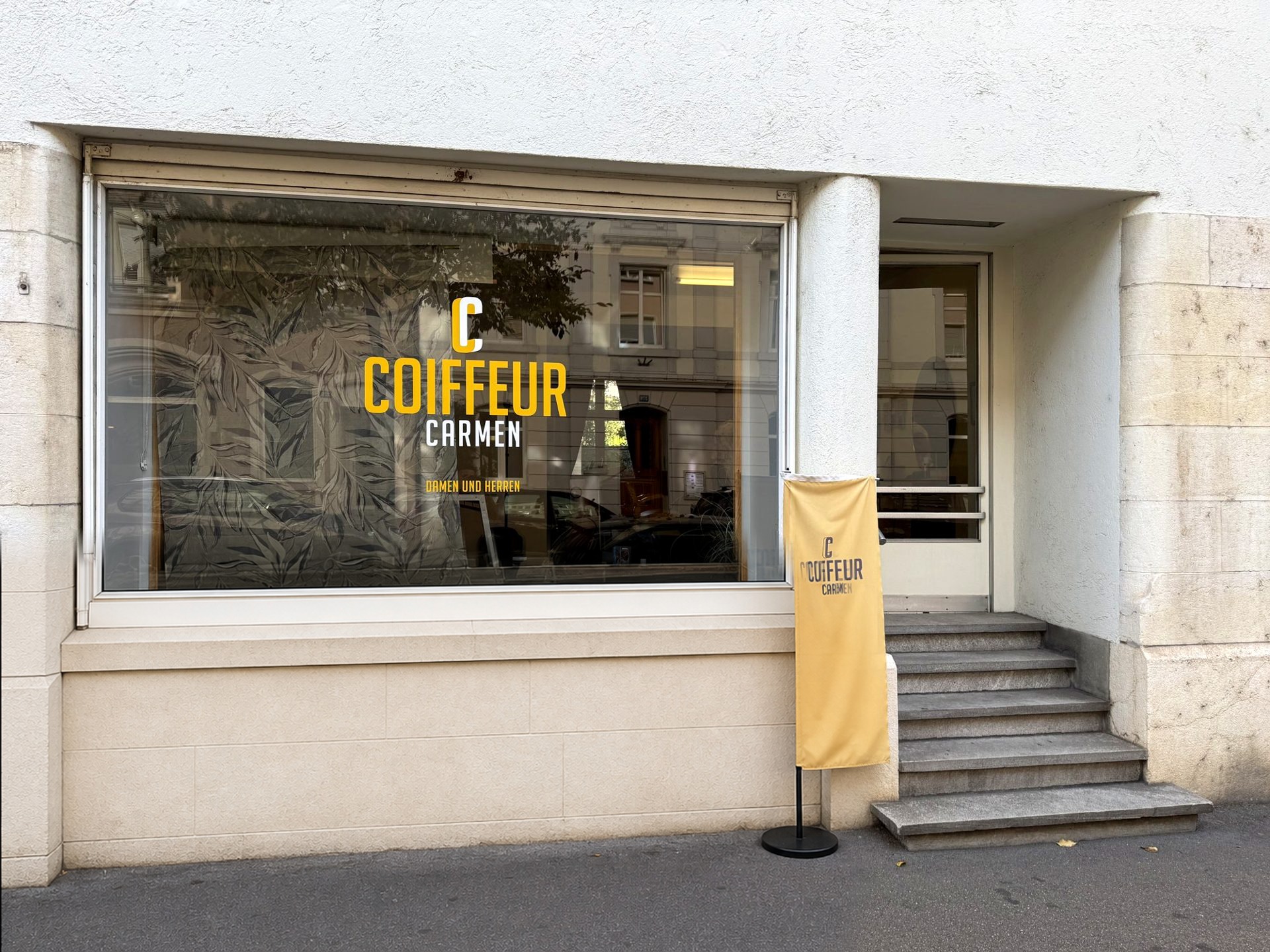 Schaufenster von Coiffeur Carmen an der Güterstrasse 277 mit gelbem Banner
